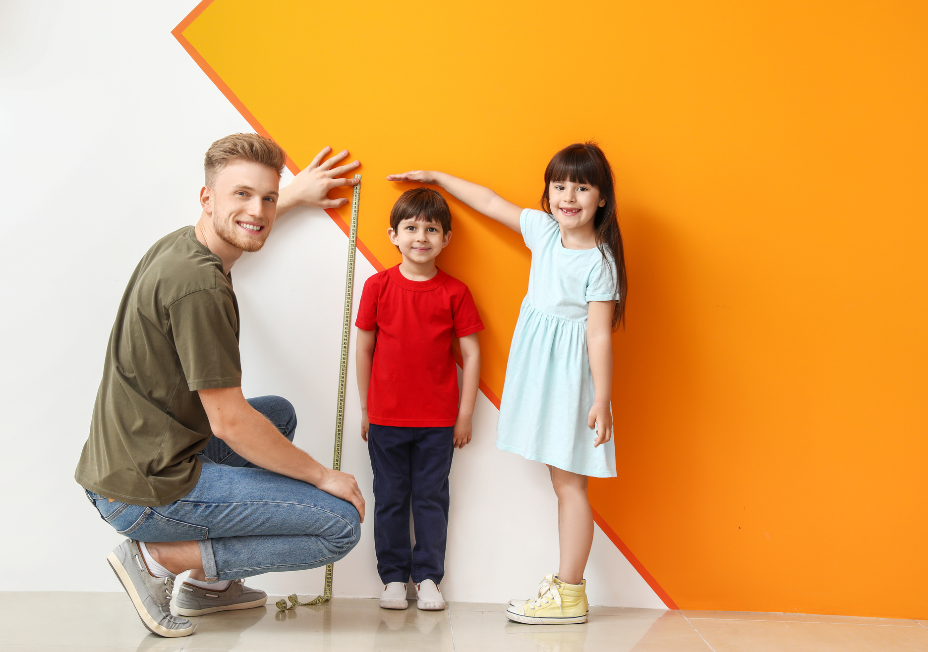 Father and His Little Children Measuring Height near Wall